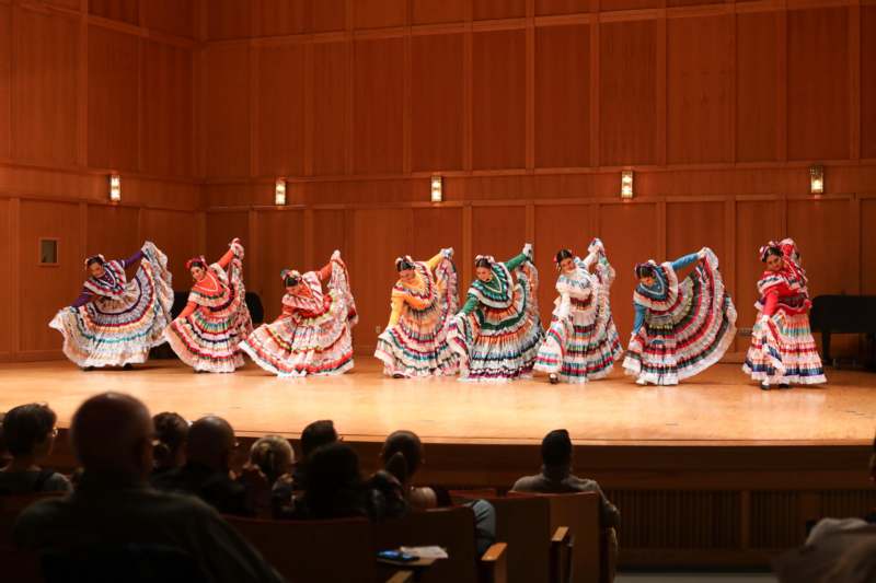 a group of women in colorful dresses on a stage