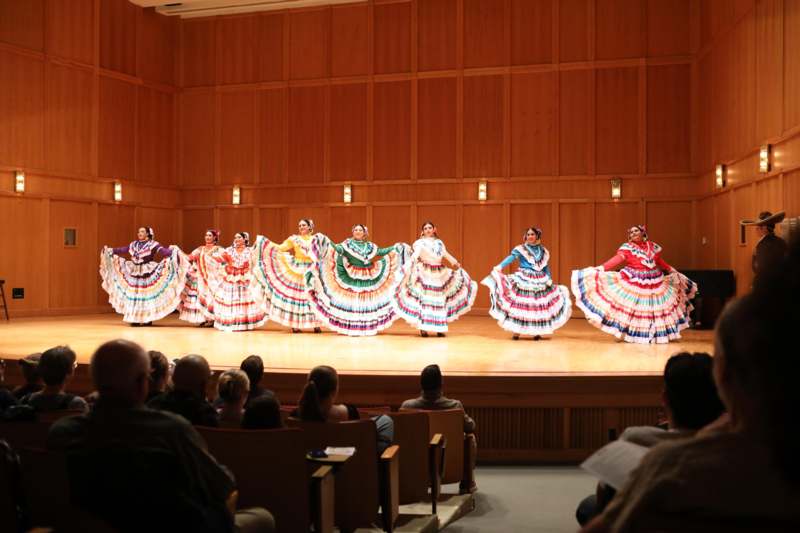 a group of women wearing colorful dresses on a stage