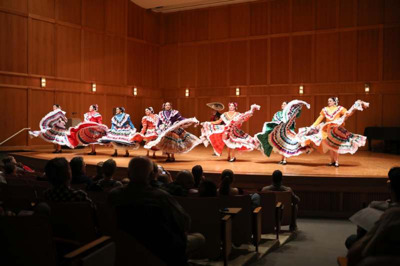 a group of women wearing colorful dresses on a stage
