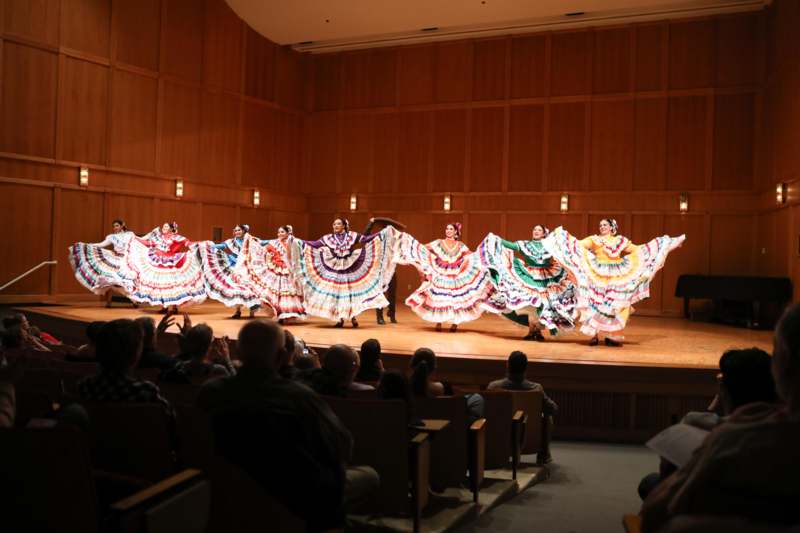 a group of women in colorful dresses performing on a stage