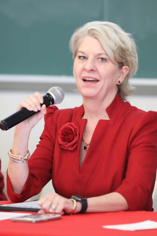 a woman in a red suit speaking into a microphone