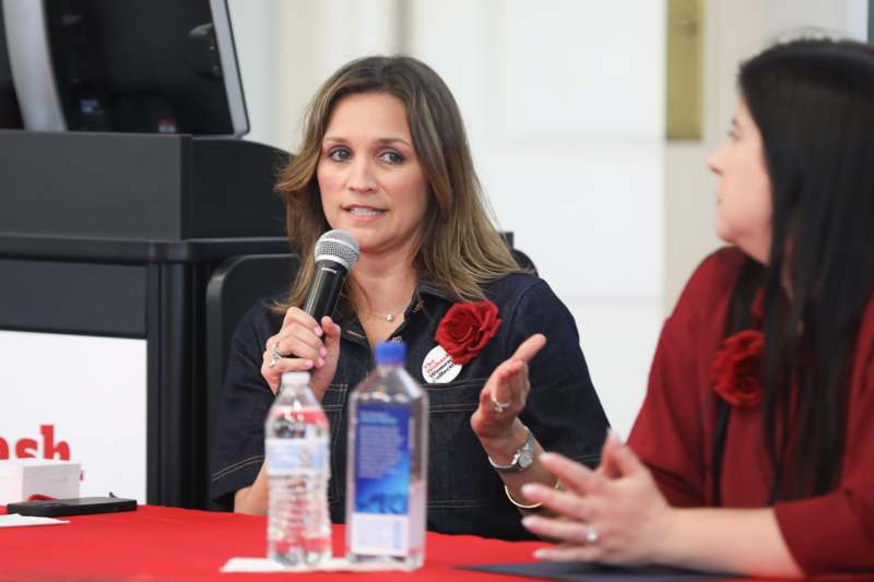 a woman holding a microphone and talking to another woman