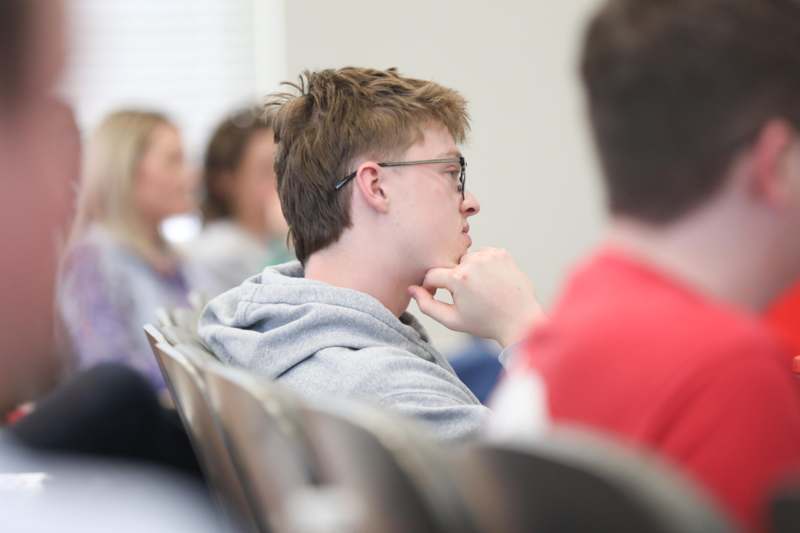a man in glasses sitting in a classroom