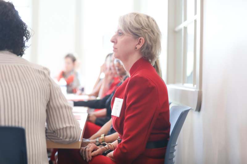 a woman in a red suit sitting at a table