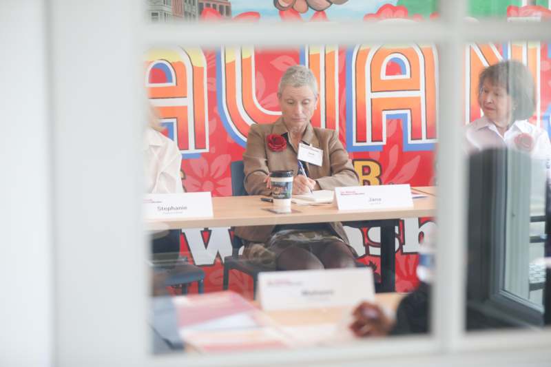 a woman sitting at a table with a cup and name tag