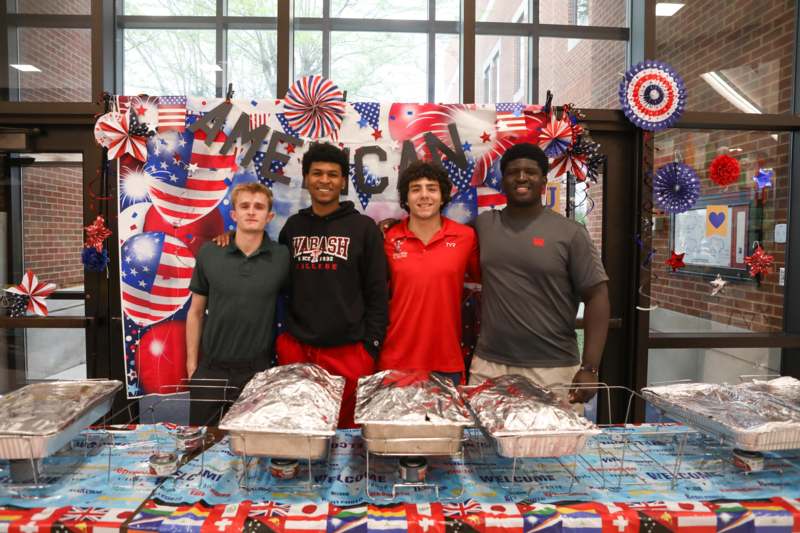 a group of men standing in front of a table with food on it