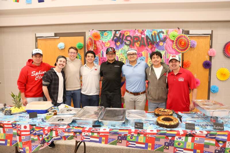 a group of people standing in front of a table with food