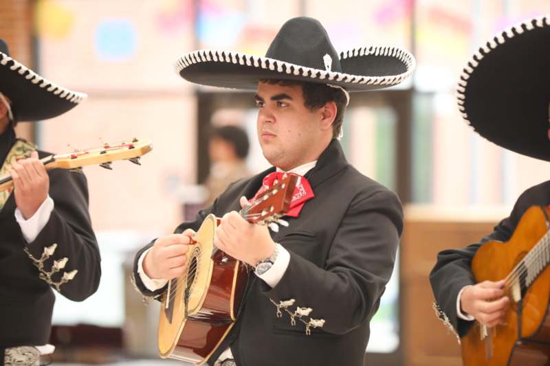 a group of men wearing mariachi suits and a sombrero playing a guitar