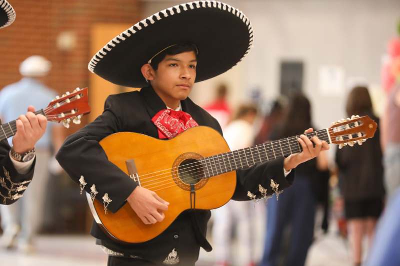 a boy wearing a sombrero playing a guitar