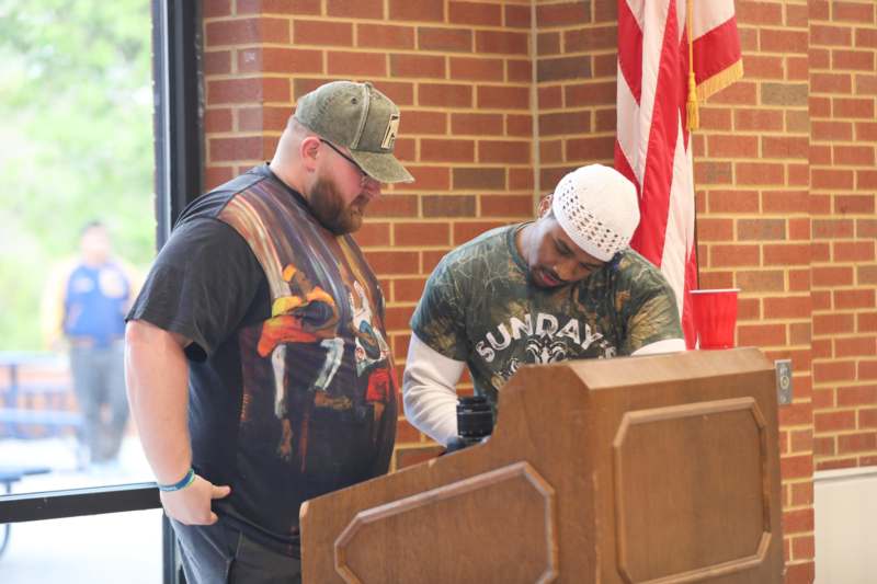 a man standing next to another man standing at a podium