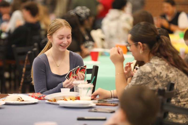 a group of people sitting at a table playing cards