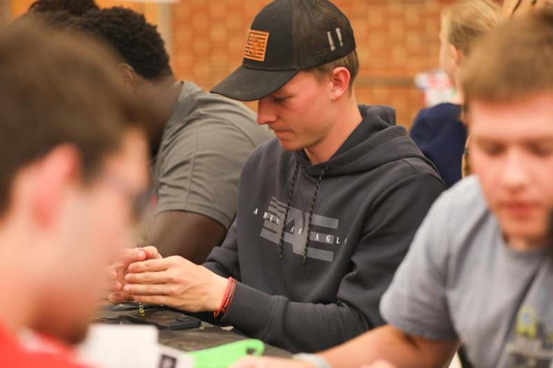 a man wearing a black hat and grey sweatshirt sitting at a table