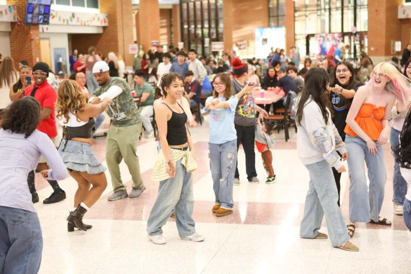 a group of people dancing in a room with a large crowd