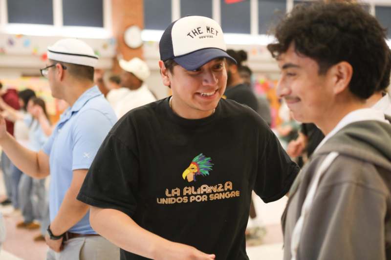 a man in a black shirt and white hat talking to another man