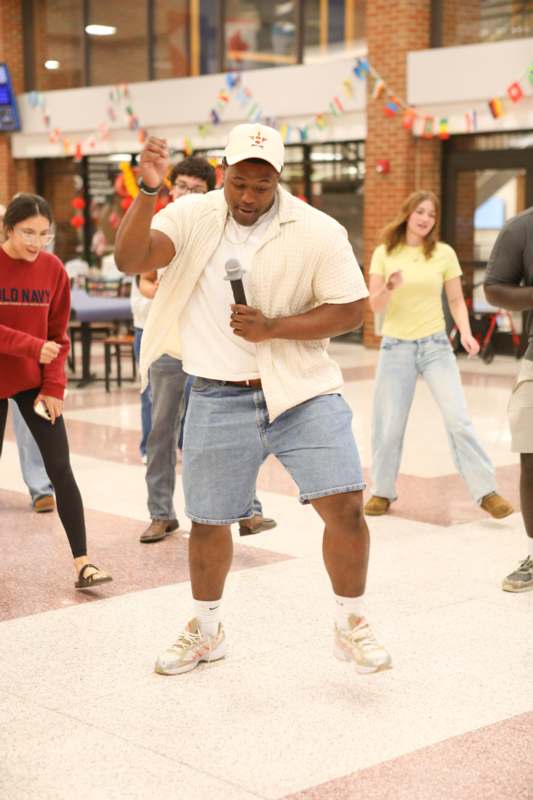 a man holding a microphone in a room with people in the background