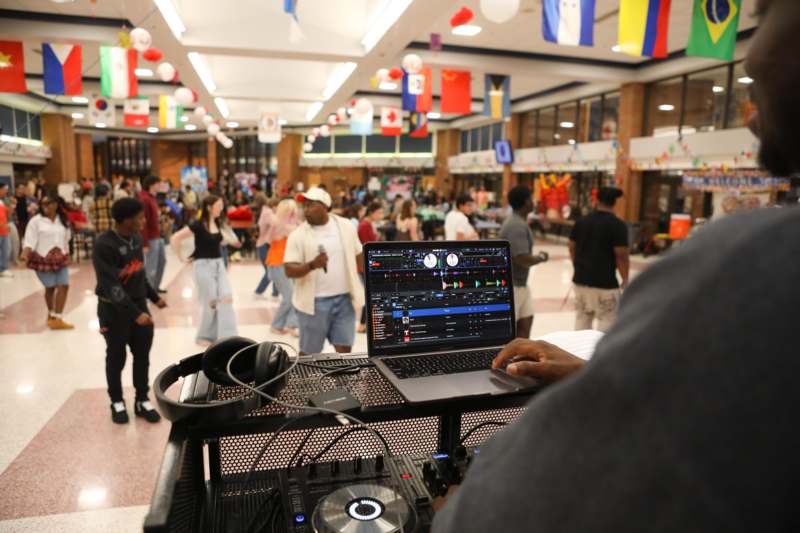 a person using a laptop in a room with people in the background