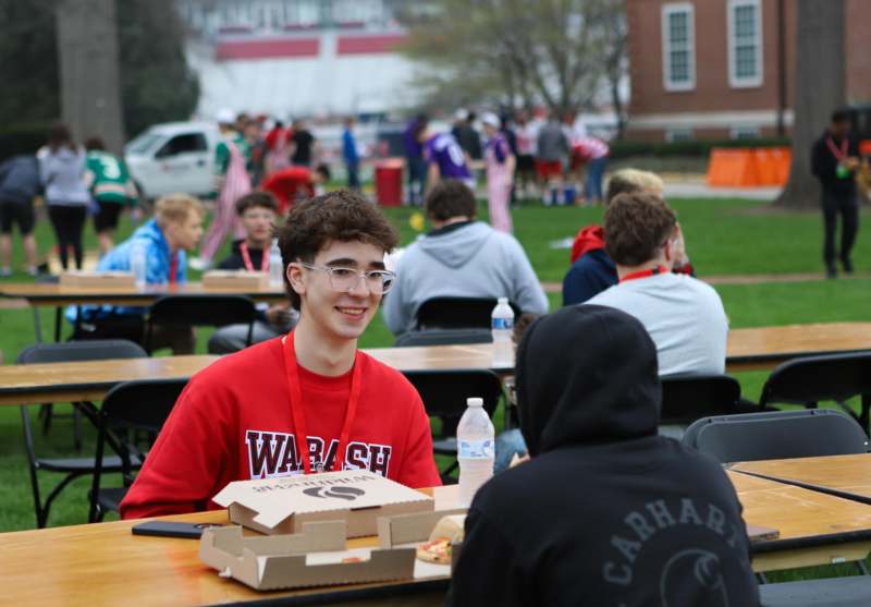 a man sitting at a table with food and people in the background