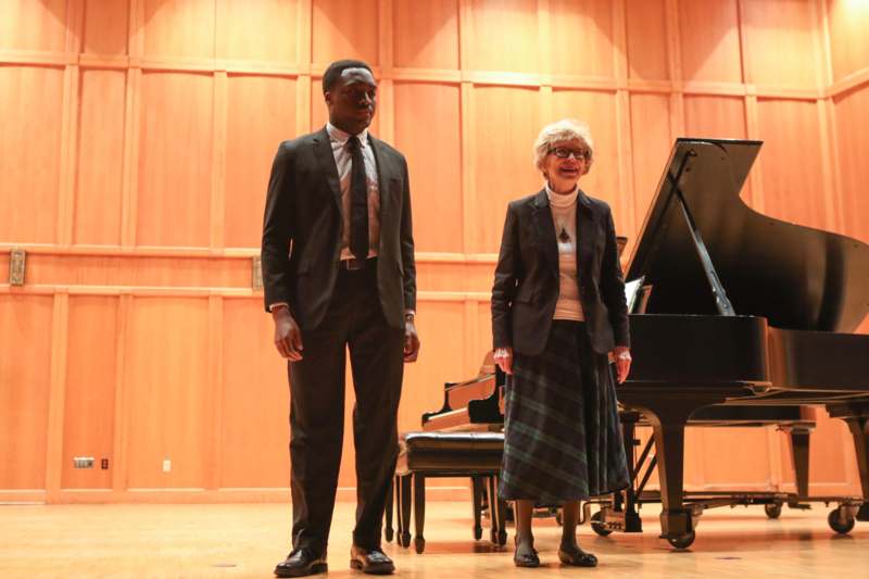 a man and woman standing in front of a piano