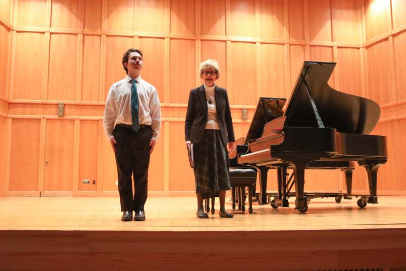 a man and woman standing on a stage with a piano