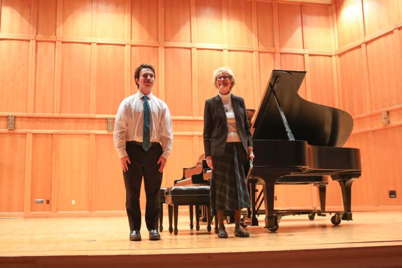a man and woman standing on a stage with a piano