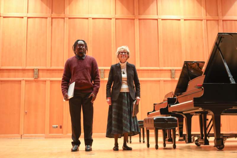 a man and woman standing in front of a piano