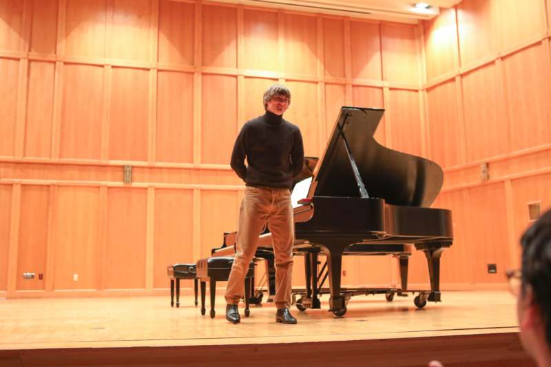 a man standing next to a piano
