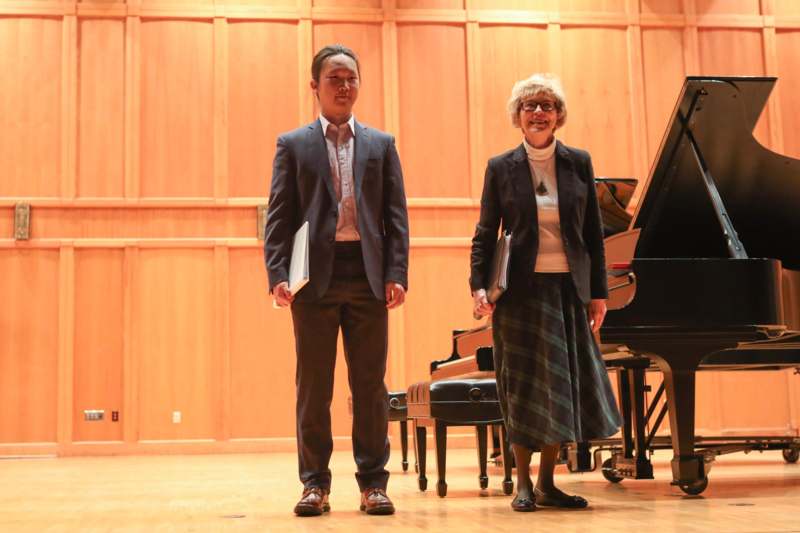 a man and woman standing in front of a piano