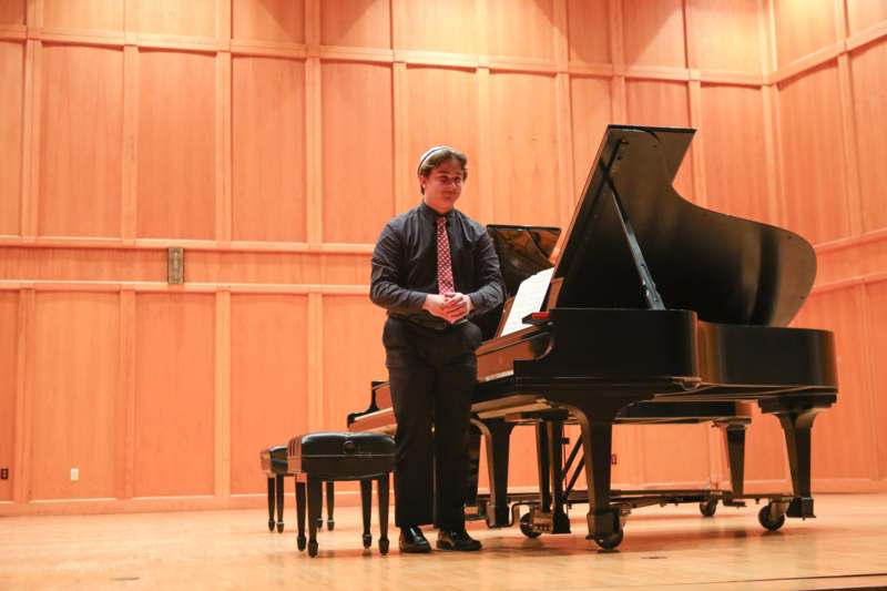a man standing next to a piano