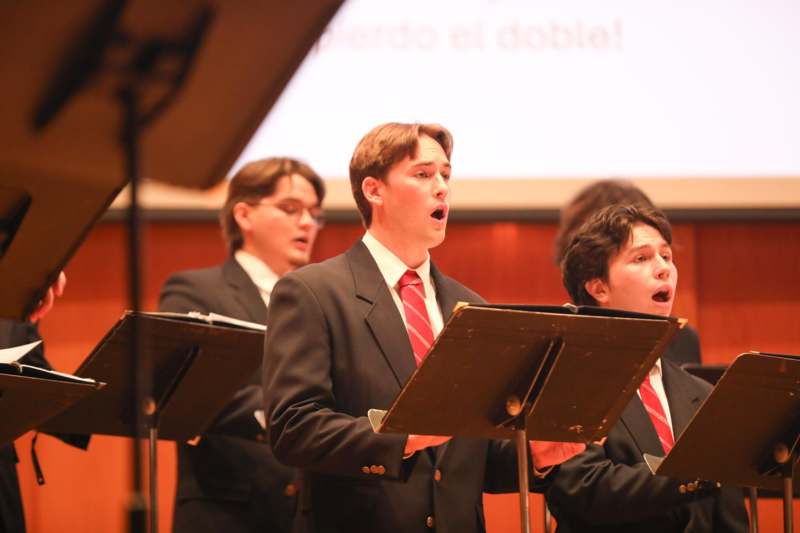 a group of men in suits singing at a concert