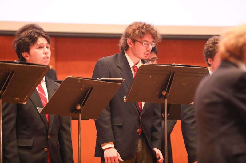 a group of men in suits and ties performing in front of a screen