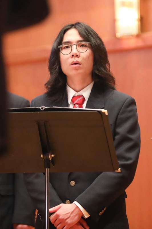 a man in a suit and tie standing at a music stand