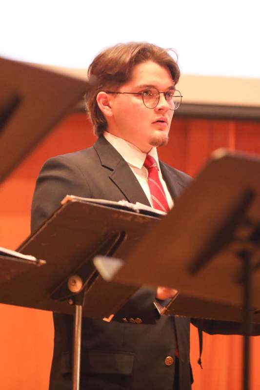 a man in a suit and tie standing in front of a music stand