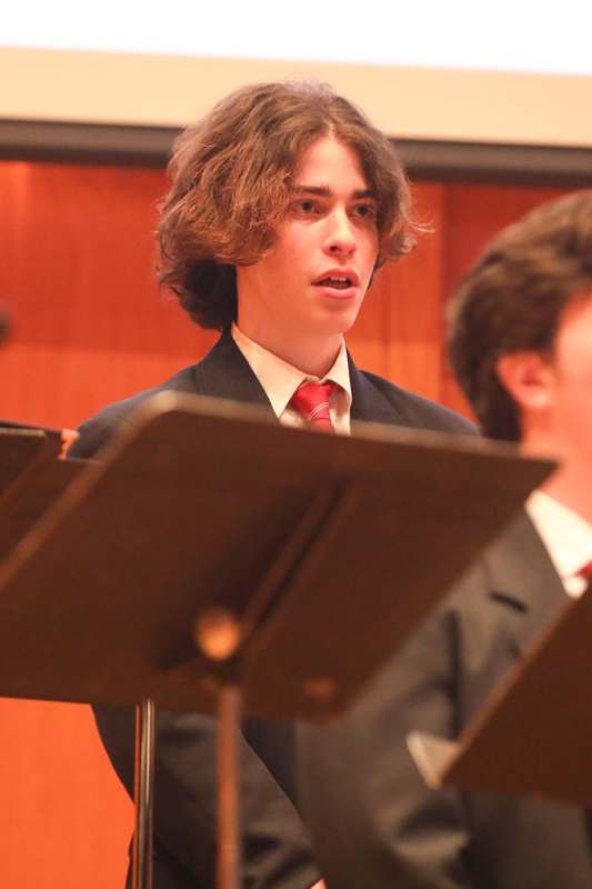 a man in a suit and tie standing in front of a music stand