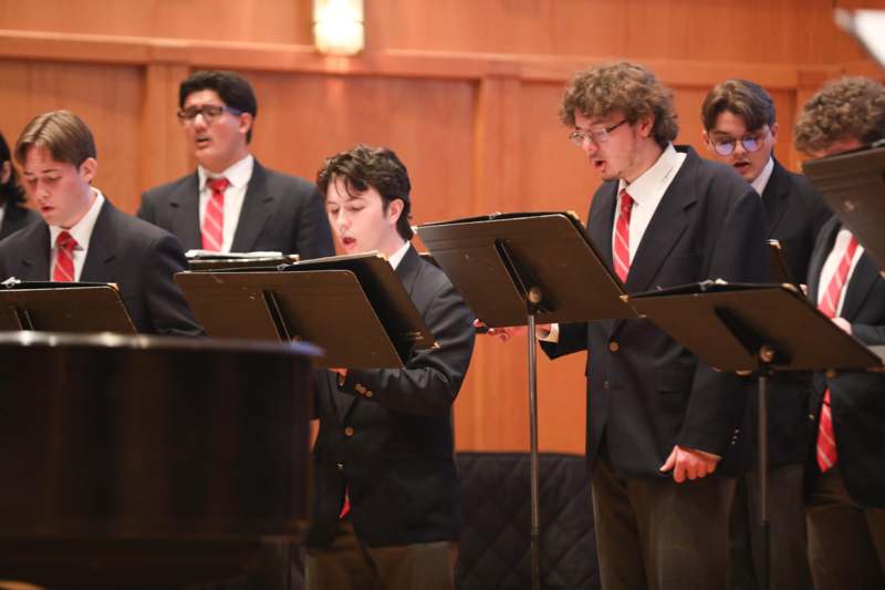 a group of people singing in front of a piano
