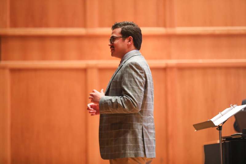 a man in a suit standing in front of a wood wall