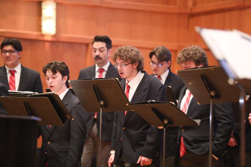 a group of men wearing suits and standing in front of a group of people