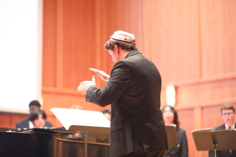 a man in a black suit and white hat standing in front of a podium