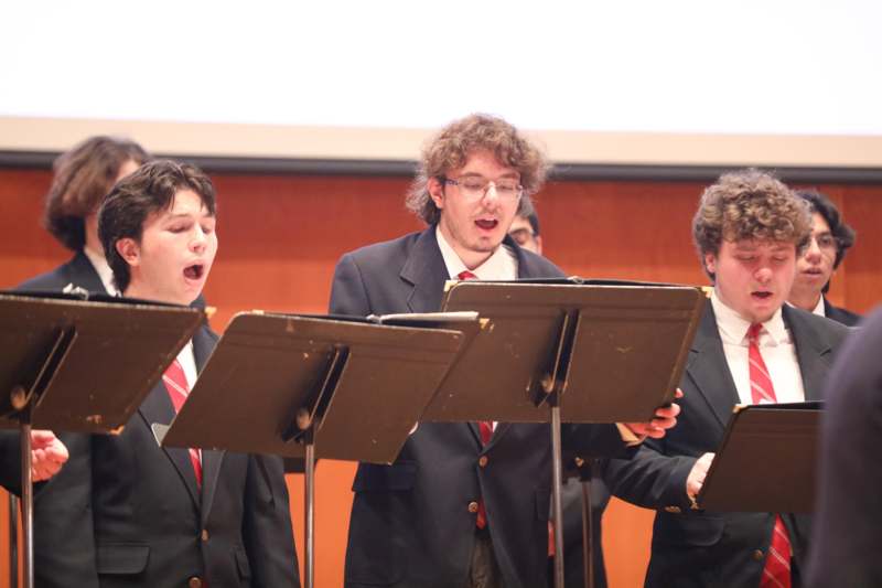 a group of men singing in front of a screen