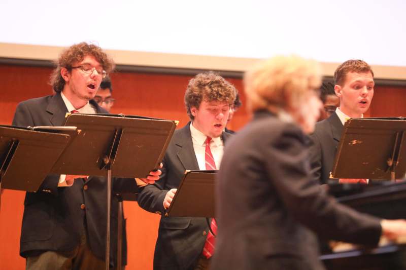 a group of people singing in front of a stage