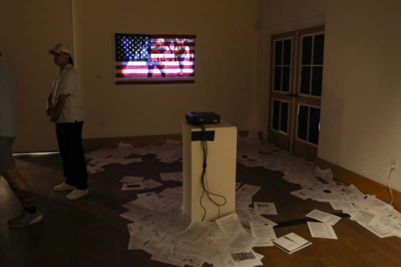 a person standing in a room with a projector and a flag