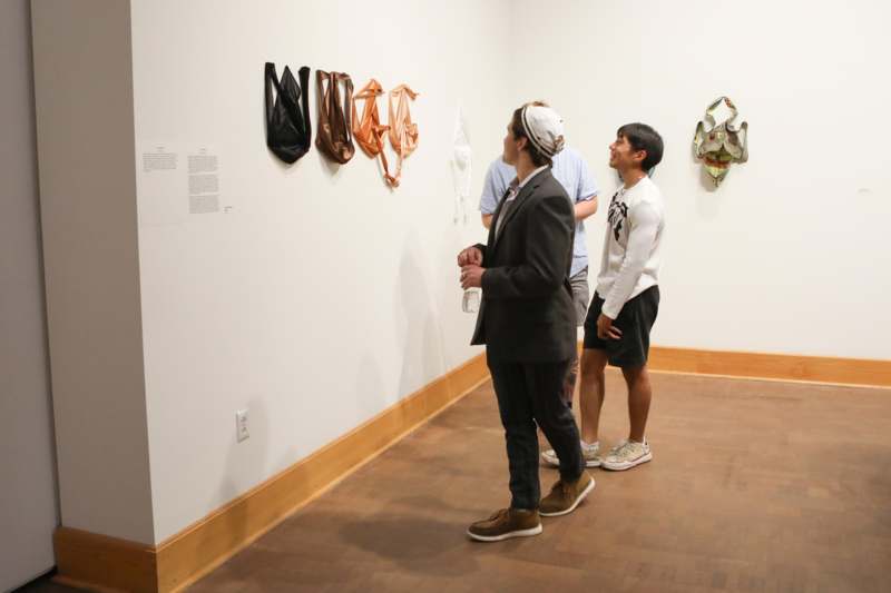 a group of people looking at a wall with bags on it