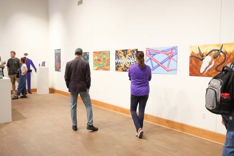 a man and woman looking at art on a wall
