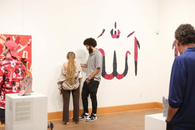 a man and woman looking at a piece of art on a wall