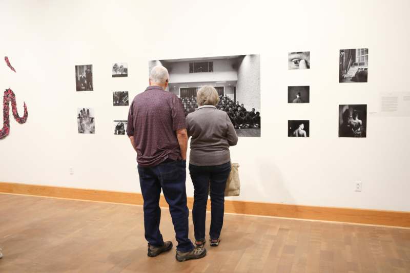 a man and woman looking at a photograph on a wall