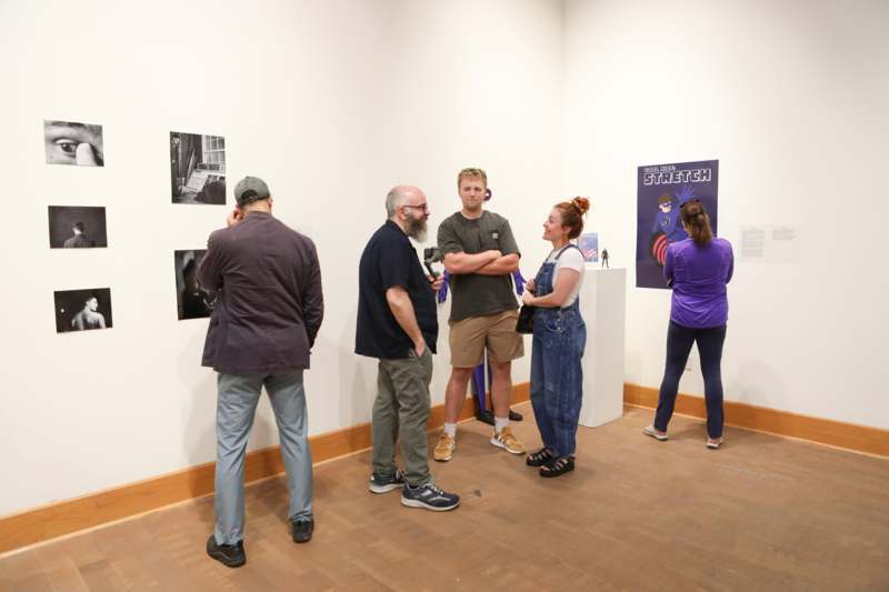 a group of people standing in a room with pictures on the wall