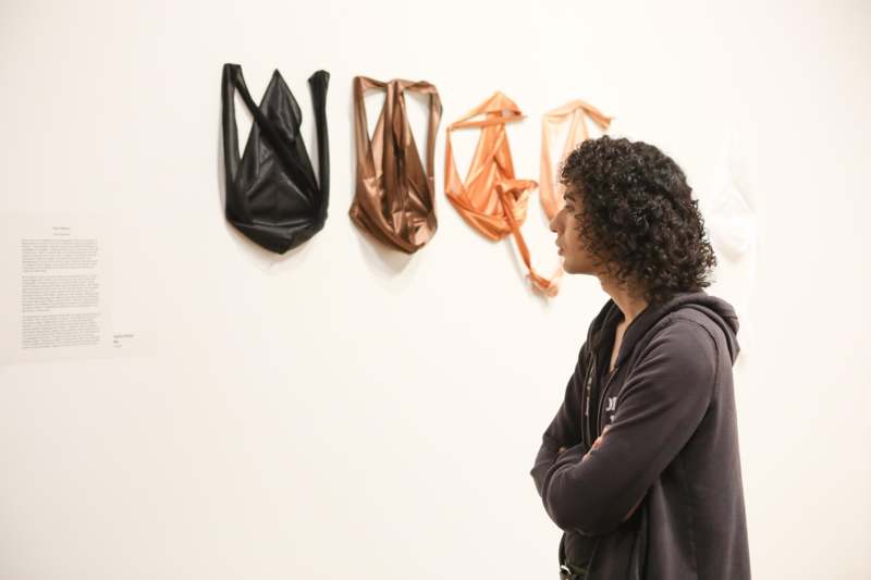 a woman looking at a wall with a few bags on it