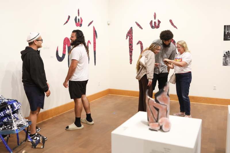 a group of people standing in a room with art on the wall