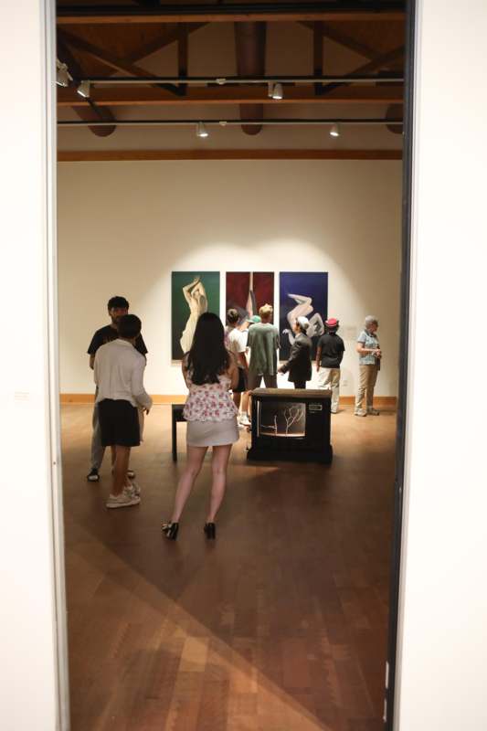 a group of people in a room with paintings on the wall