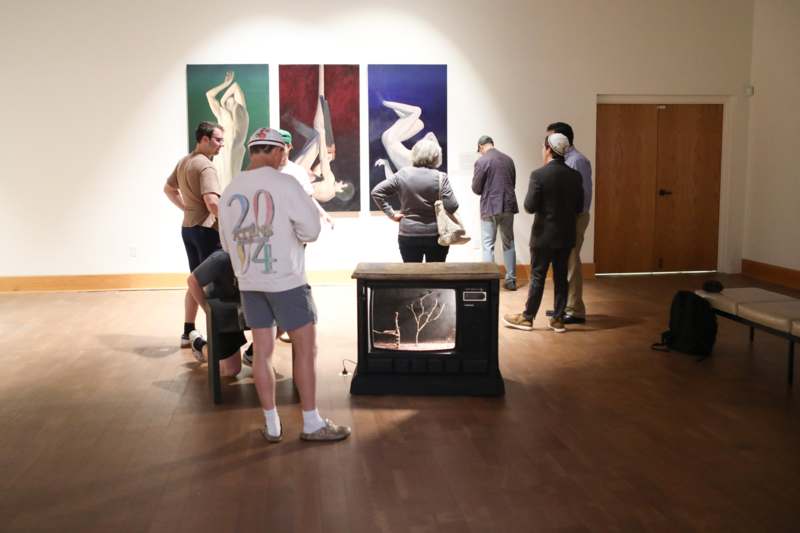 a group of people in a room with paintings on the wall