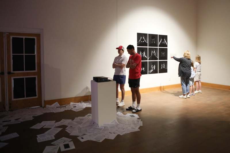 a group of people standing in a room with a pile of papers on the floor